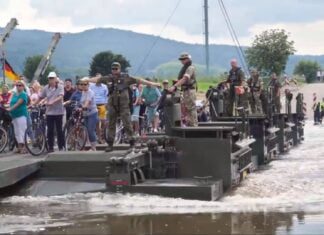 a Militares ajudando a população a atravessar o rio. a Militares ajudando a população a atravessar o rio.