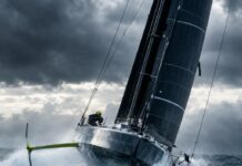 Editorial Photography Of A High-Performance Imoca 60 Offshore Racing Sailboat With Hydrofoils, Heeling And Flying Across…