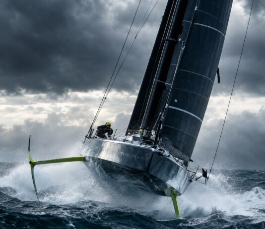 Editorial Photography Of A High-Performance Imoca 60 Offshore Racing Sailboat With Hydrofoils, Heeling And Flying Across…