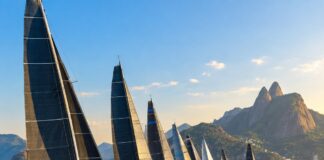 Refeno 2026: recorde de embarcações larga em busca de destronar o Adrenalina Pura Fleet of racing sailboats at the starting line of an offshore ocean regatta, dramatic wide shot, blue tropical ocean, cl…