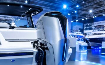 Fotografia Realista De Um Motor De Popa Moderno E Futurista Instalado Na Traseira De Uma Lancha Branca, Em Um Salão Náut…