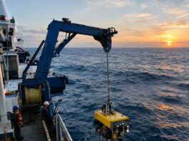 Fotografia realista de um navio de pesquisa oceanográfica no meio do Oceano Atlântico, em alto-mar, com um ROV (veículo …