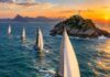 Regata Santos-Rio terá nova chegada na Ilha Rasa em 2026 Veleiros oceânicos de competição navegando em mar aberto perto de uma pequena ilha rochosa na costa do Rio de Janeiro, a…