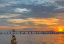 Fotografia realista da Baía de Guanabara, Rio de Janeiro, mostrando a ponte Rio-Niterói ao fundo e uma boia de sinalizaç…