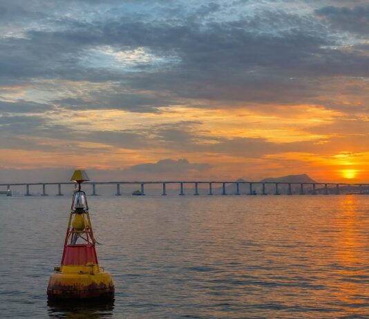 Fotografia realista da Baía de Guanabara, Rio de Janeiro, mostrando a ponte Rio-Niterói ao fundo e uma boia de sinalizaç…